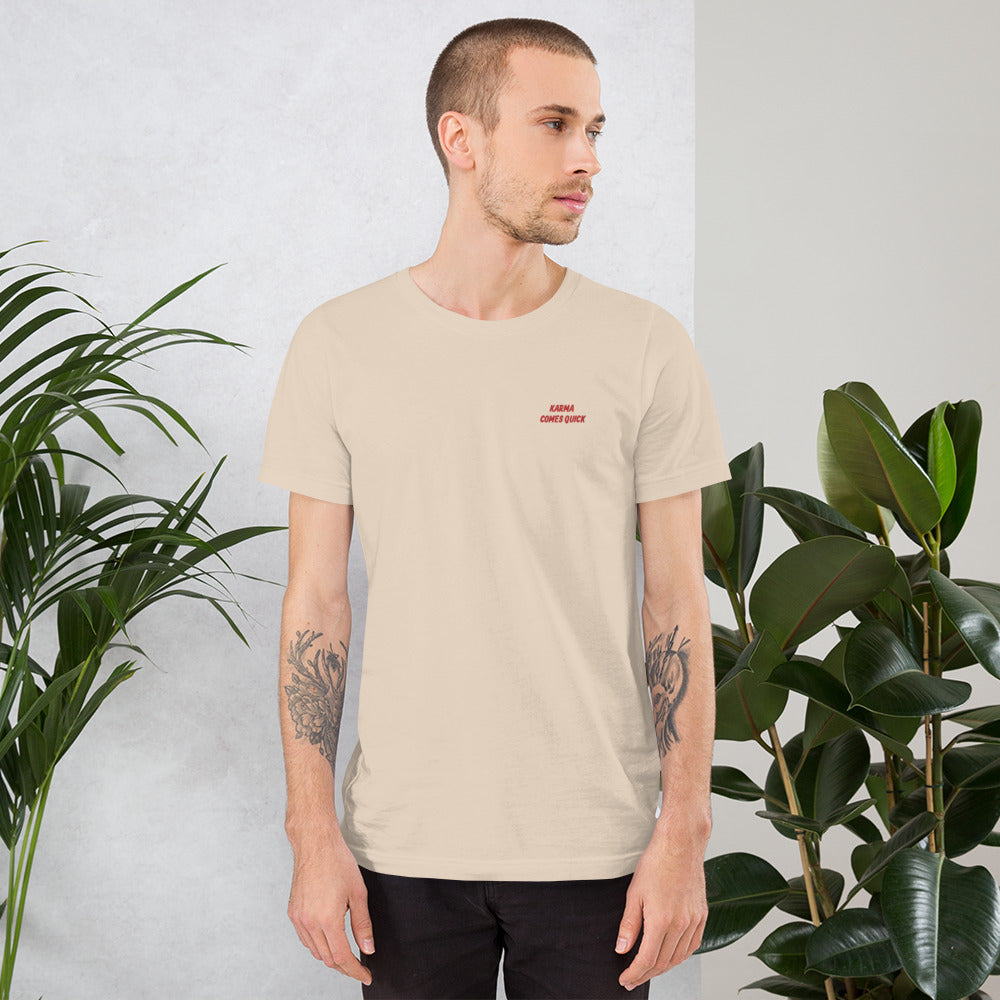 Man wearing NOMADA Karma Comes Quick embroidered t-shirt, Soft cream color shirt
